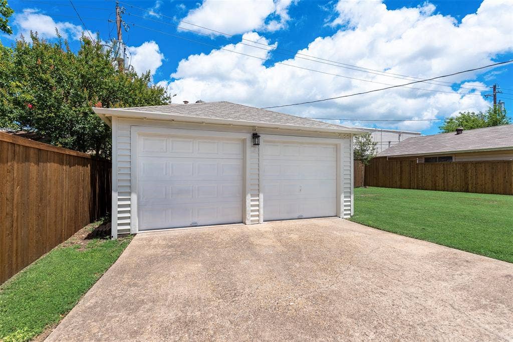 2523 San Medina Avenue, Dallas, TX 75228 Two-car garage with white paneled doors, exterior lighting, and concrete driveway