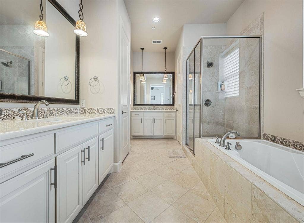 5001 Meridian Lane, #2103, Addison, TX 75001 Spacious bathroom featuring a double vanity with white cabinetry, a tiled backsplash, and stone-finish countertops