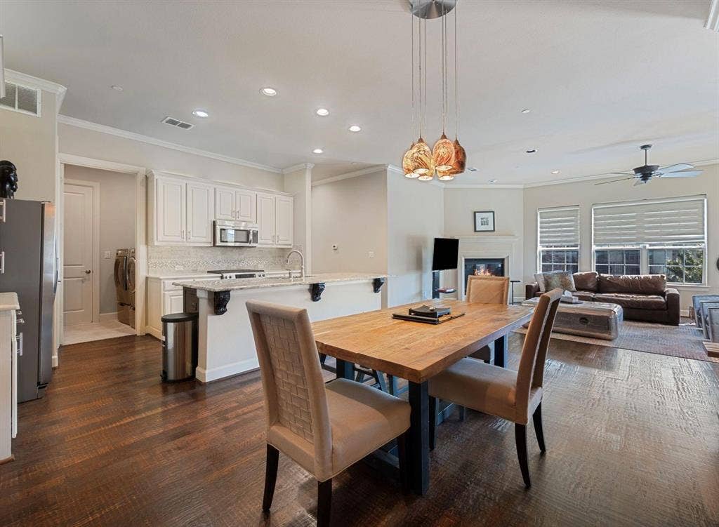5001 Meridian Lane, #2103, Addison, TX 75001 Open-concept living space featuring wood-finish flooring, a kitchen island with stone countertops, white cabinetry, and a stainless steel microwave
