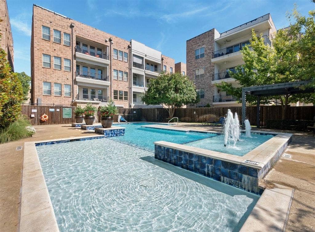 5001 Meridian Lane, #2103, Addison, TX 75001 Resort-style pool area featuring a water fountain, blue mosaic tile accents, and a surrounding paved deck