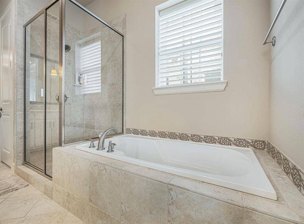 5001 Meridian Lane, #2103, Addison, TX 75001 Soaking tub with decorative tile surround, complemented by a glass-enclosed shower with tile walls