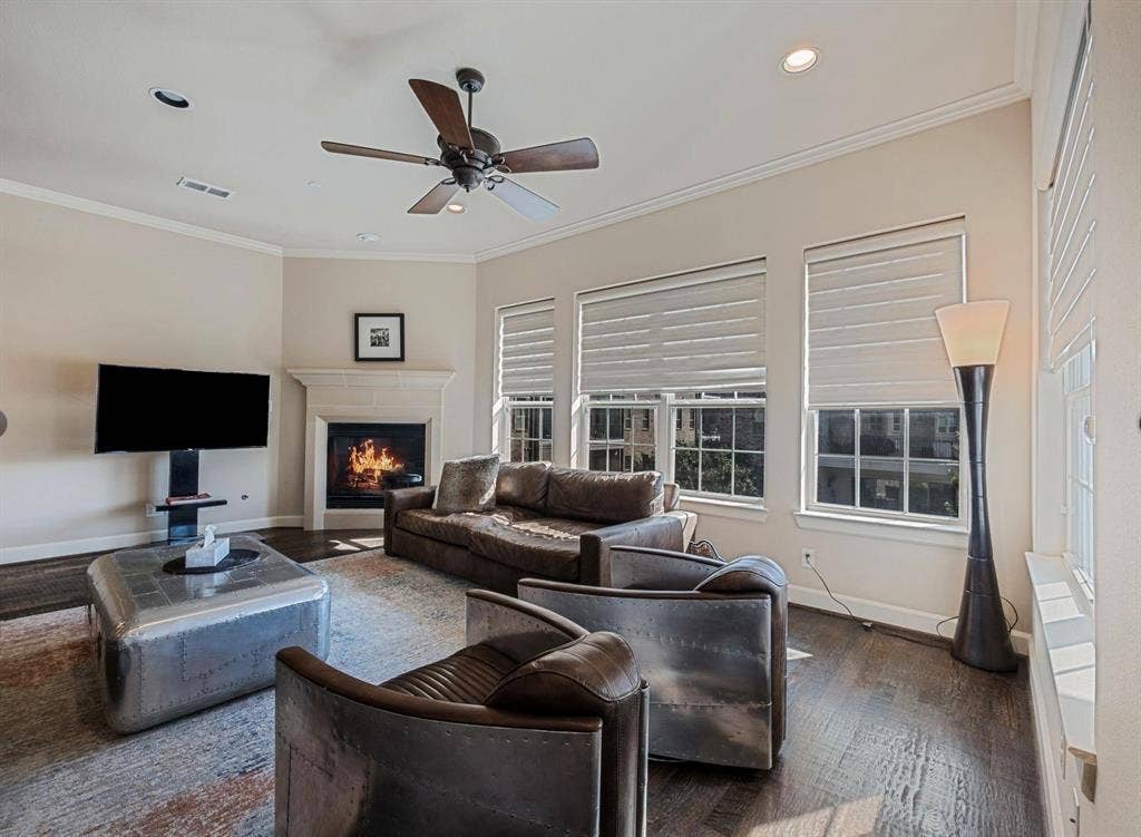 5001 Meridian Lane, #2103, Addison, TX 75001 Living area featuring wood-finish flooring, a corner fireplace with a stone mantel, multiple windows with blinds, a ceiling fan, and recessed lighting