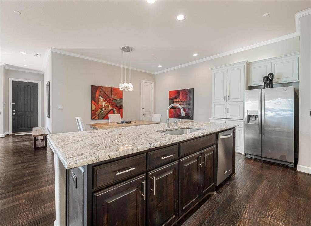 5001 Meridian Lane, #2103, Addison, TX 75001 Kitchen island featuring a light-toned countertop, integrated sink with a gooseneck faucet, and dark-finish cabinetry