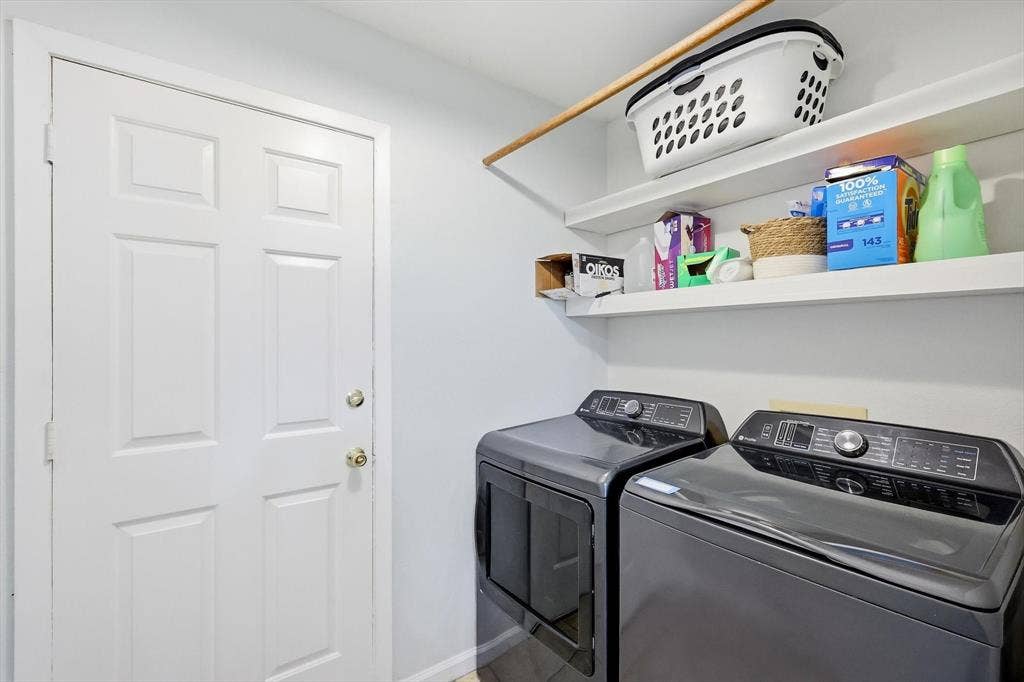437 Bradshaw Street, Cedar Hill, TX 75104 Dedicated laundry area featuring modern dark grey washer and dryer units, two white floating shelves, and a wooden hanging rod