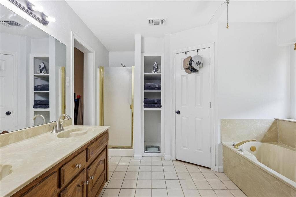 437 Bradshaw Street, Cedar Hill, TX 75104 Bathroom featuring a wood-finish vanity with a light-toned countertop, a built-in bathtub, a shower enclosure, and white tile flooring