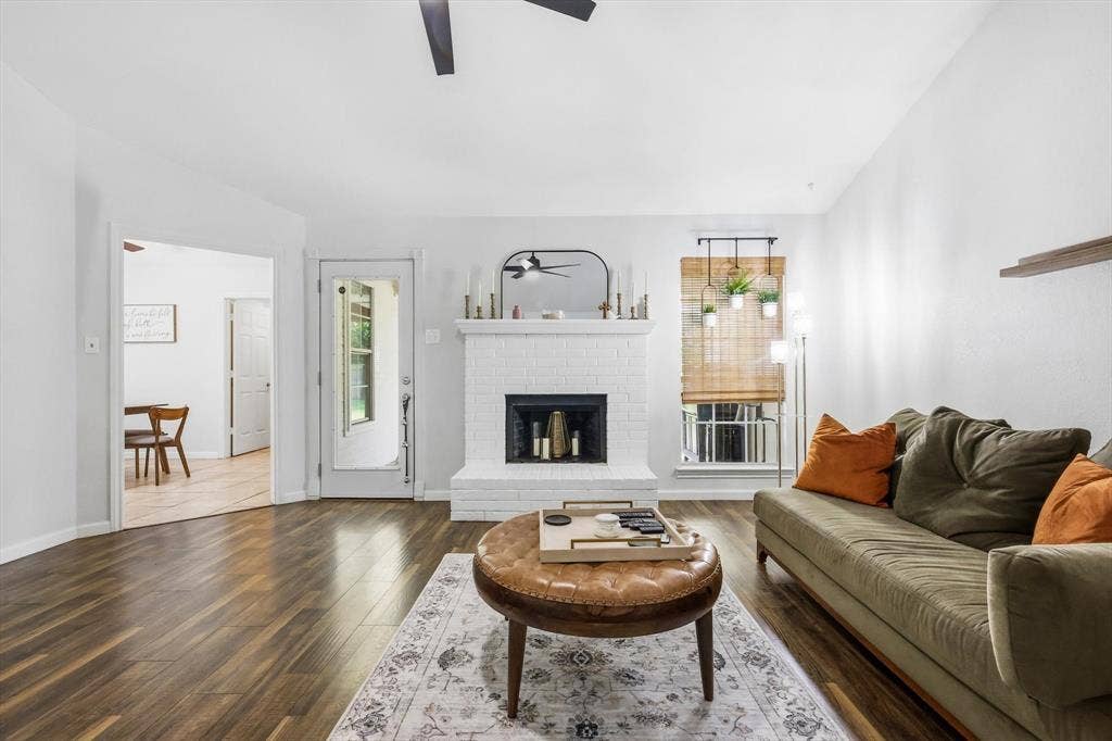 437 Bradshaw Street, Cedar Hill, TX 75104 Living area featuring wood-finish flooring, a white brick fireplace, a ceiling fan, a window with a bamboo shade, and a glass-paneled door