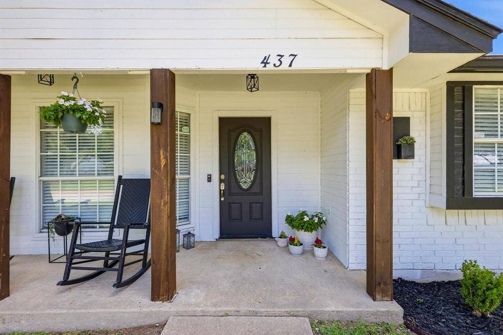 437 Bradshaw Street, Cedar Hill, TX 75104 Covered front porch featuring robust wood-look columns, a decorative glass-paneled entry door, white siding, and a large window with white blinds