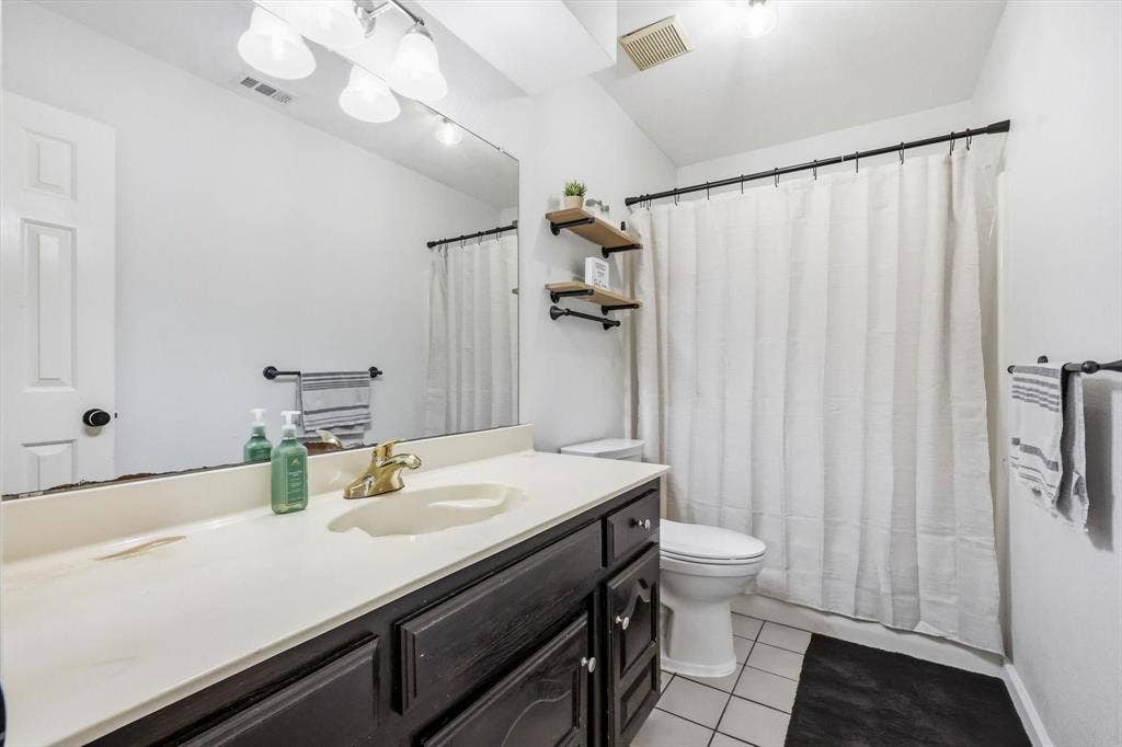 437 Bradshaw Street, Cedar Hill, TX 75104 Bathroom featuring a dark wood-finish vanity with a single basin, a gold-tone faucet, and a large wall-mounted mirror