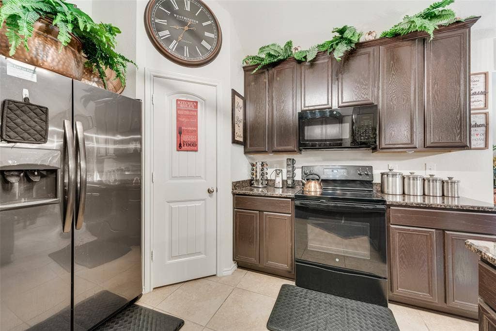 301 Billy Wickliffe Drive, Wilmer, TX 75172 Kitchen featuring wood-finish cabinetry, stone countertops, stainless steel refrigerator, black electric range, and tile flooring