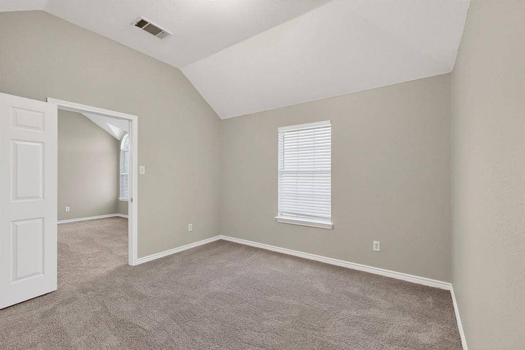 217 Gatehouse Drive, Red Oak, TX 75154 Spacious room featuring vaulted ceilings, neutral-toned walls, and grey carpeting