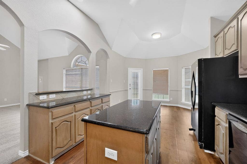 217 Gatehouse Drive, Red Oak, TX 75154 Kitchen featuring a central island with a dark countertop, wood-finish flooring, and light-toned cabinetry