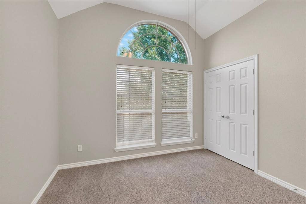 217 Gatehouse Drive, Red Oak, TX 75154 Vaulted ceiling with an arched transom window, dual pane windows with blinds, gray wall paint, white baseboards, and carpeted flooring