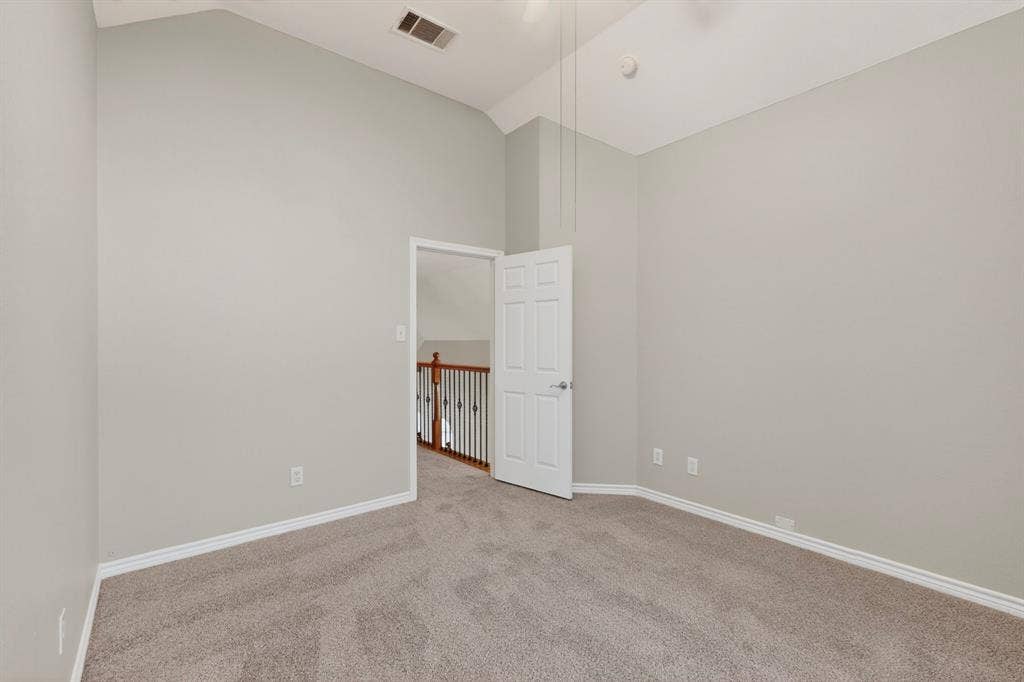 217 Gatehouse Drive, Red Oak, TX 75154 Carpeted interior space featuring neutral wall tones, vaulted ceilings, white trim, and a white interior door