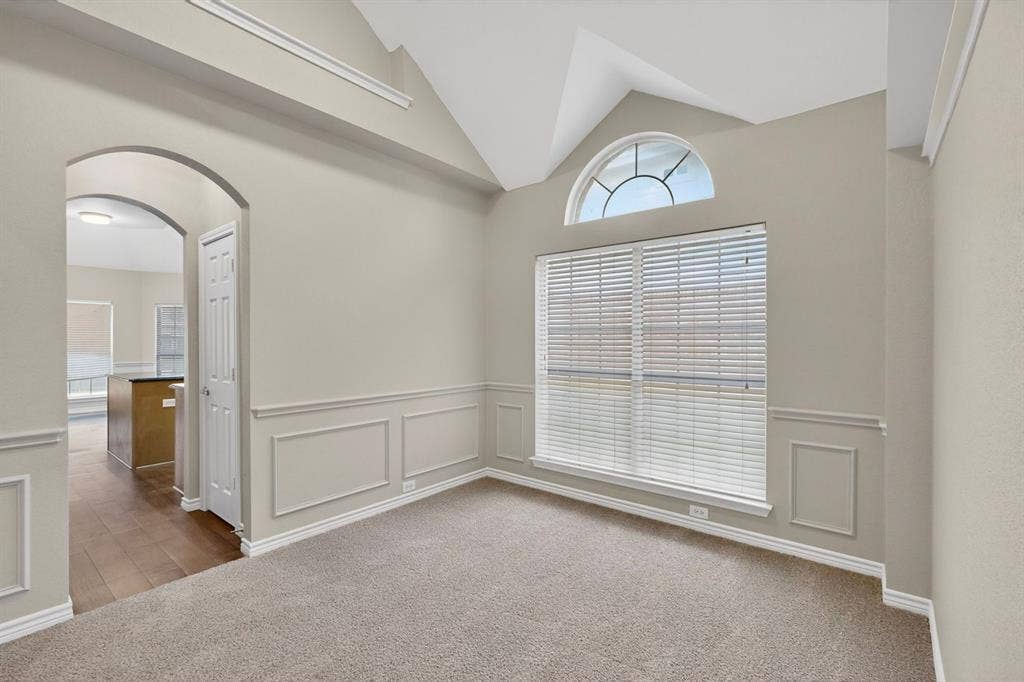 217 Gatehouse Drive, Red Oak, TX 75154 Vaulted ceiling with an arched transom window above a large rectangular window, complemented by wainscoting and crown molding details