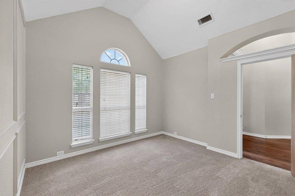 217 Gatehouse Drive, Red Oak, TX 75154 Vaulted ceiling office featuring light gray carpeting, multiple windows with blinds, an arched transom window, and a paneled accent wall