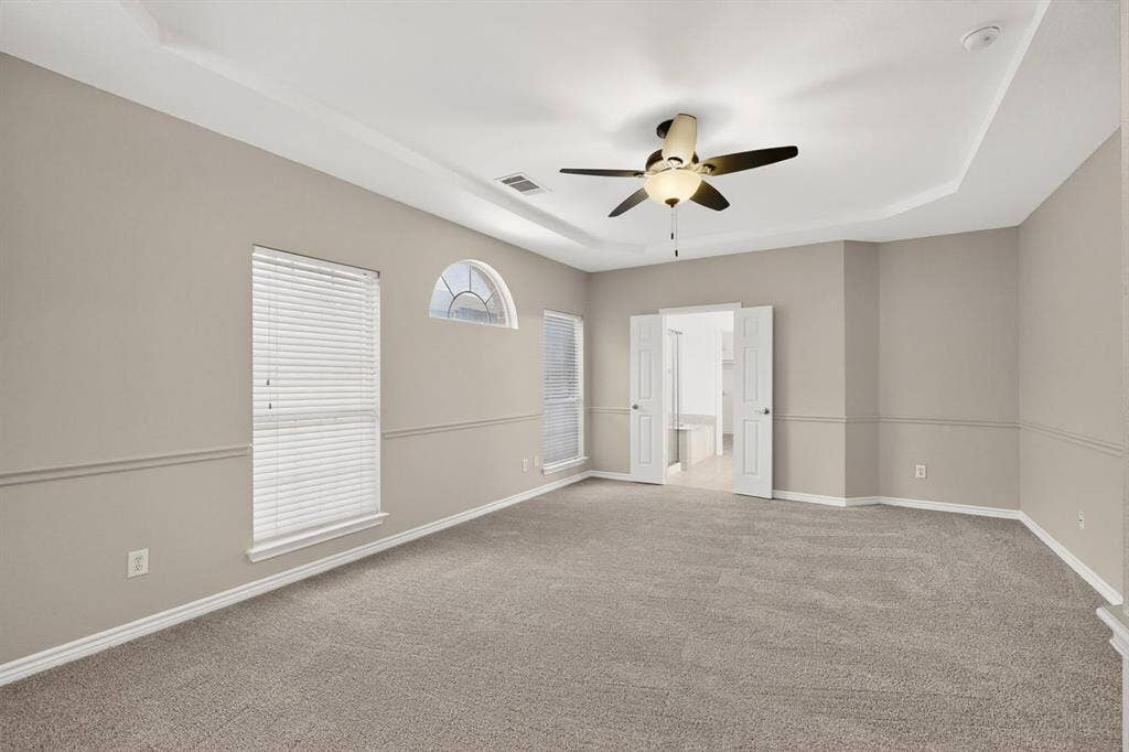 217 Gatehouse Drive, Red Oak, TX 75154 Spacious primary bedroom featuring tray ceiling, ceiling fan, and carpeted flooring
