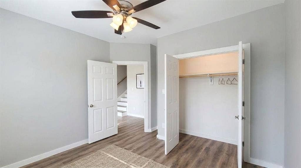 9114 Caddo Road, #A & B, Houston, TX 77078 Bedroom 1 - Downstairs Virtually Staged Spacious room featuring vinyl flooring, light gray walls, white trim, a ceiling fan with integrated lighting, and a closet with bifold doors