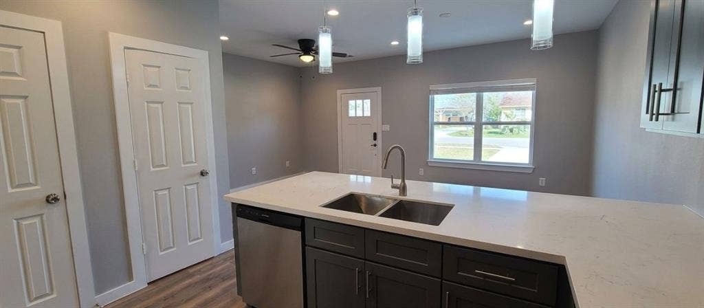 9114 Caddo Road, #A & B, Houston, TX 77078 Kitchen island featuring a double basin stainless steel sink, a stainless steel dishwasher, and a light-toned countertop