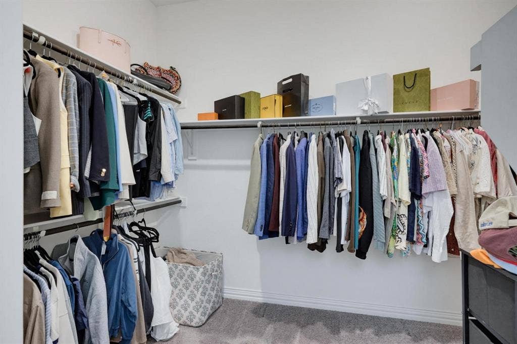 1205 Shady Fox Way, Arlington, TX 76005 Walk-in closet featuring extensive built-in shelving, multiple hanging rods, white walls, gray carpet flooring, and white baseboards