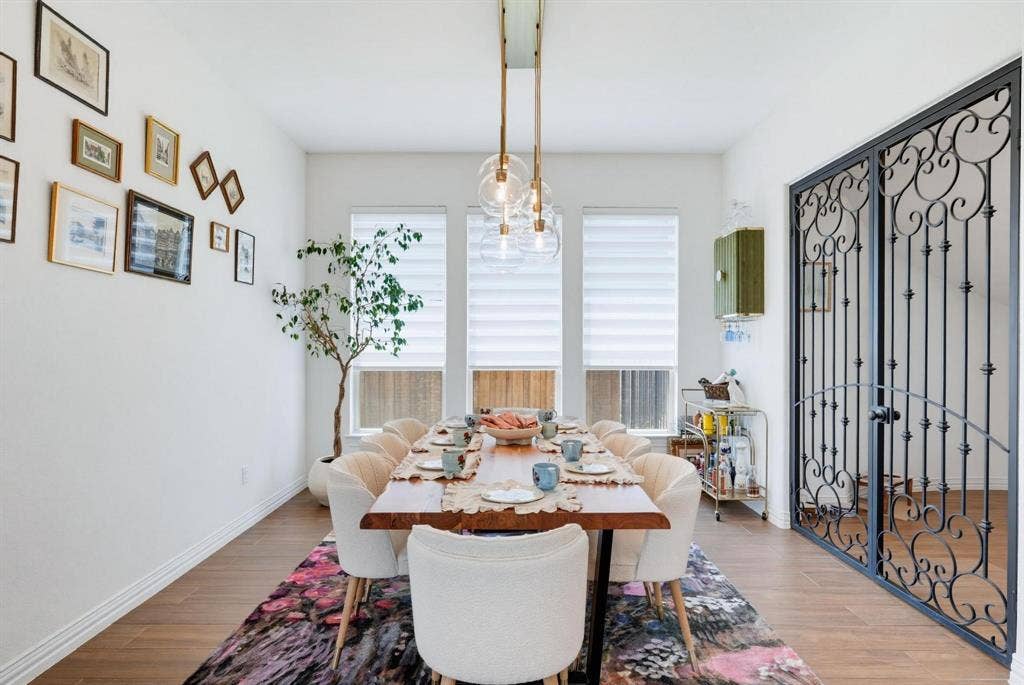 1205 Shady Fox Way, Arlington, TX 76005 Dining area featuring wood-finish flooring, white baseboards, and a modern linear chandelier with glass globes