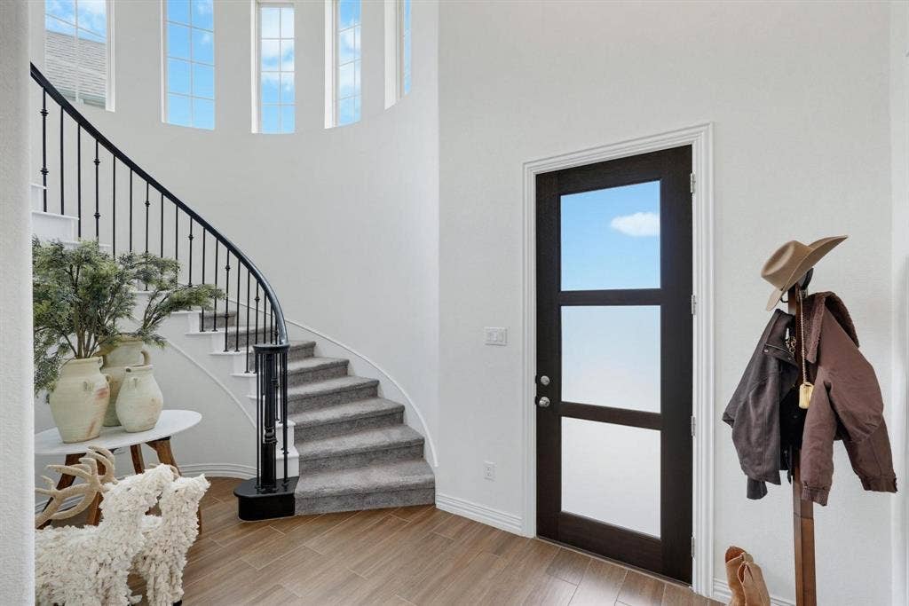 1205 Shady Fox Way, Arlington, TX 76005 Grand entryway featuring a curved staircase with wrought iron balusters and carpeted treads, wood-finish flooring, a modern door with three frosted glass panels, and upper-level arched windows