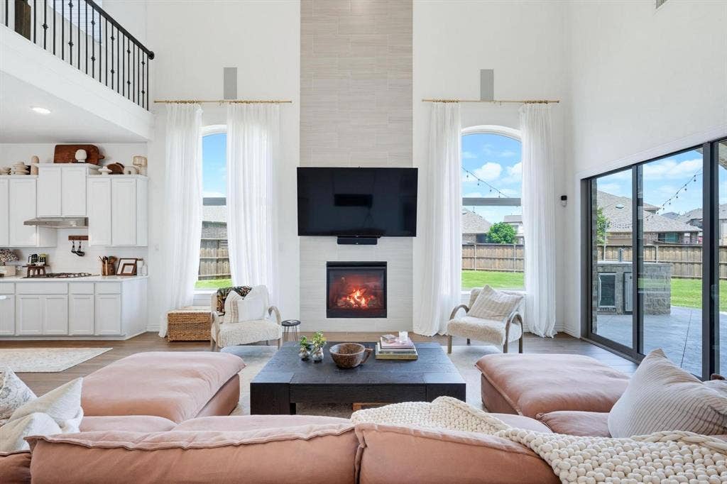1205 Shady Fox Way, Arlington, TX 76005 Two-story great room featuring a contemporary fireplace with a tile surround, wood-finish flooring, and a second-story balcony with metal balusters
