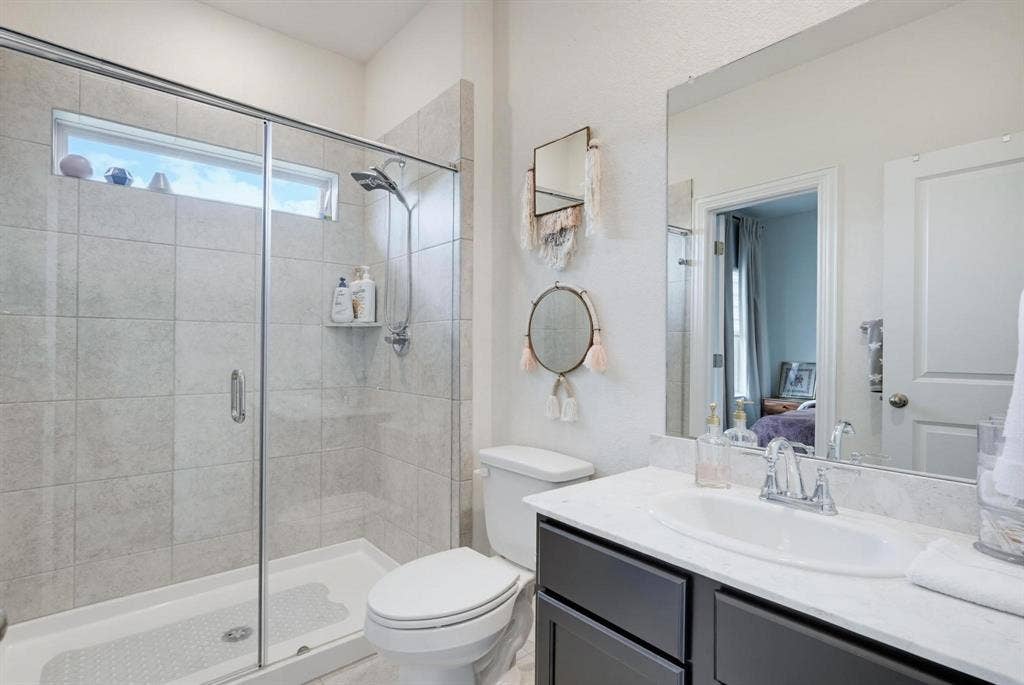 1205 Shady Fox Way, Arlington, TX 76005 Modern bathroom featuring a glass-enclosed shower with tile surround and a transom window