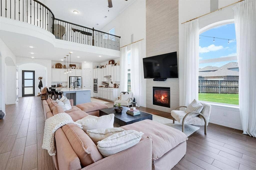 1205 Shady Fox Way, Arlington, TX 76005 Open-concept living space featuring wood-finish flooring, a two-story ceiling, and a fireplace with a light-toned tile surround