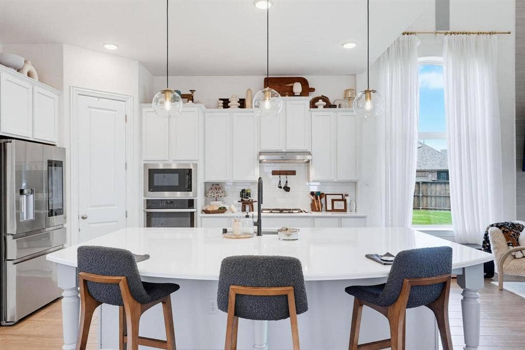 1205 Shady Fox Way, Arlington, TX 76005 Expansive kitchen featuring a large central island, white cabinetry, stainless steel appliances, and wood-finish flooring