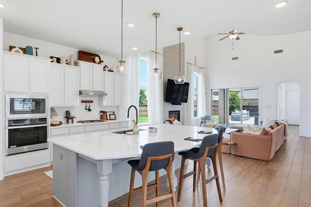 1205 Shady Fox Way, Arlington, TX 76005 Bright open-concept kitchen and living area featuring a large center island with seating, stainless steel appliances, and wood-finish flooring