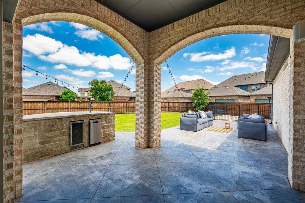 1205 Shady Fox Way, Arlington, TX 76005 Covered patio with brick arches and a stone-clad outdoor kitchen featuring built-in appliances