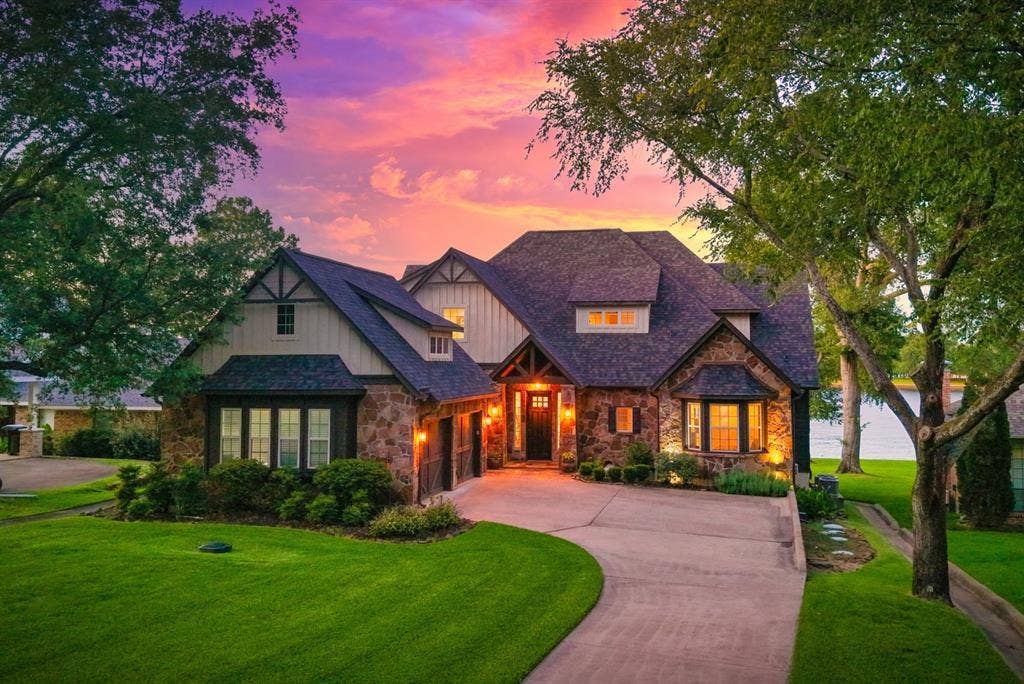 229 N Beverly Drive, Malakoff, TX 75148 Hill Country style meets classic lakehouse charm in this waterfront home with a stone and wood exterior. Street side view showing the two car garage.