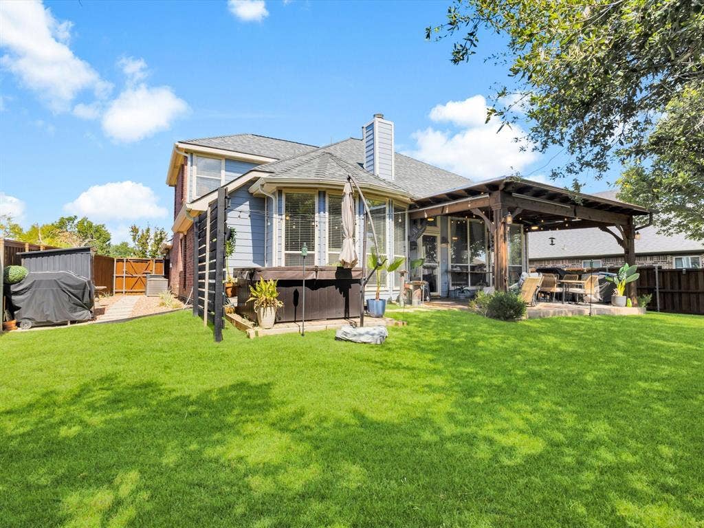 6004 Crestmill Lane, Sachse, TX 75048 Expansive backyard featuring a lush lawn, a wooden pergola-covered patio, and a privacy fence