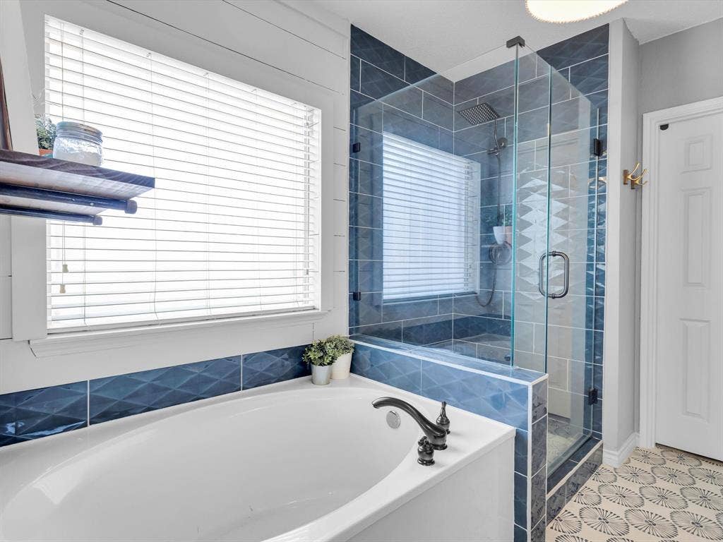6004 Crestmill Lane, Sachse, TX 75048 Soaking tub with dark bronze-finish fixtures, framed by decorative blue tile