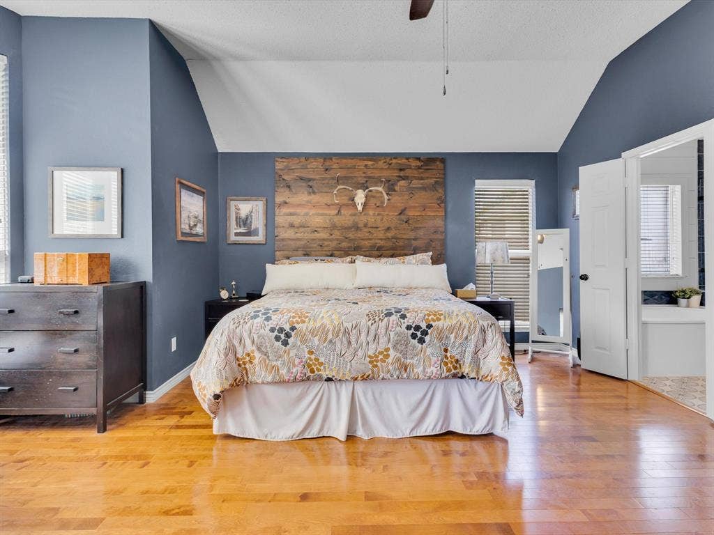 6004 Crestmill Lane, Sachse, TX 75048 Spacious bedroom featuring vaulted ceilings, wood-finish flooring, and a unique wood plank accent wall
