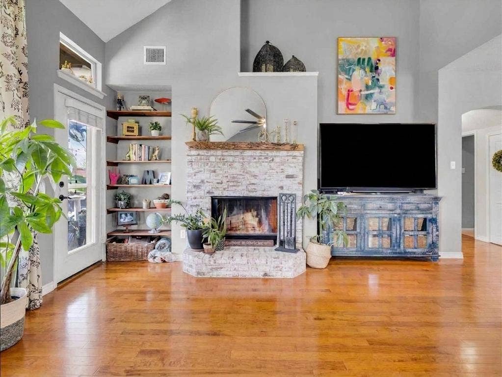 6004 Crestmill Lane, Sachse, TX 75048 Vaulted ceiling, wood-finish flooring, white-washed brick fireplace, built-in shelving, and transom windows