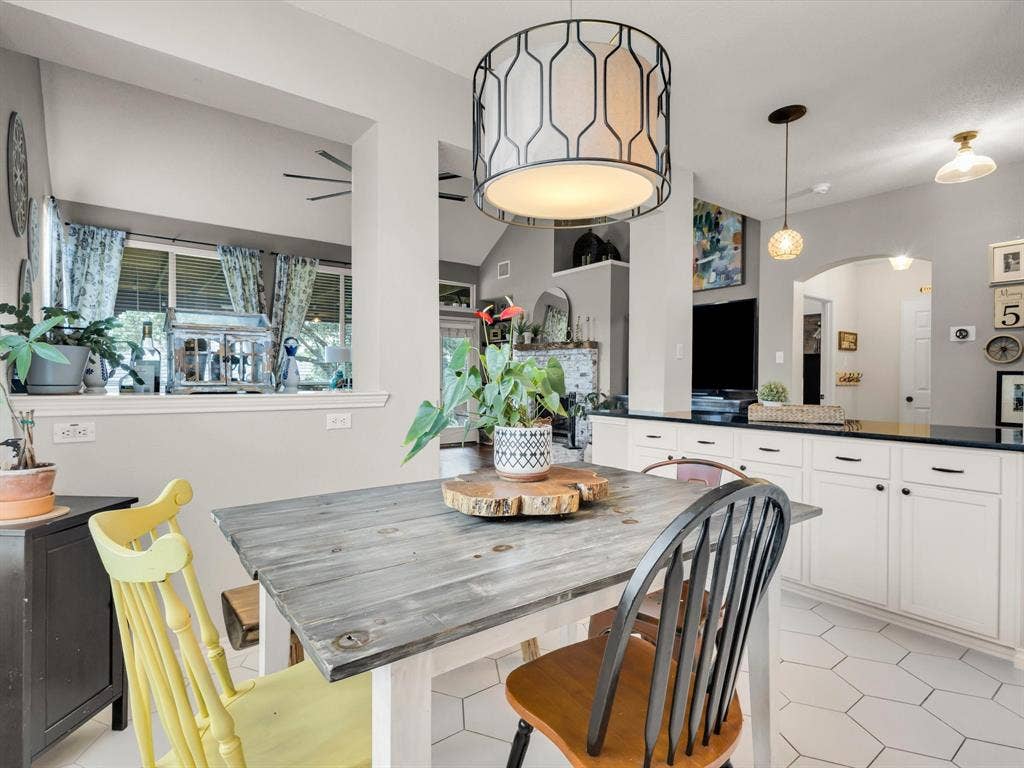 6004 Crestmill Lane, Sachse, TX 75048 Kitchen dining area featuring a geometric pendant light fixture, white hexagonal floor tiling, and a pass-through window opening
