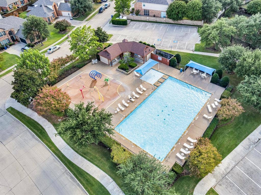 6004 Crestmill Lane, Sachse, TX 75048 Community swimming pool with an adjacent splash pad, surrounding lounge chairs, and shaded outdoor seating