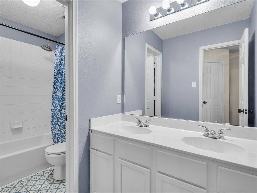 6004 Crestmill Lane, Sachse, TX 75048 Bathroom featuring a dual vanity with white cabinetry, white countertops, and chrome fixtures