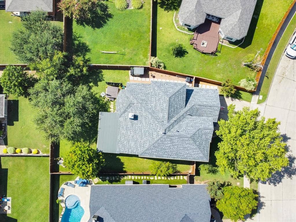 6004 Crestmill Lane, Sachse, TX 75048 Aerial perspective of a property featuring a multi-gabled roofline, a private backyard with established trees, and a concrete patio space