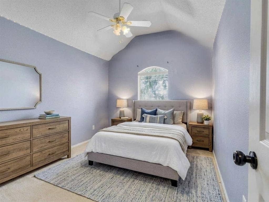 6004 Crestmill Lane, Sachse, TX 75048 Room featuring a vaulted ceiling with a ceiling fan, an arched window with blinds, and light-colored walls. This bedroom photo is virtually staged.