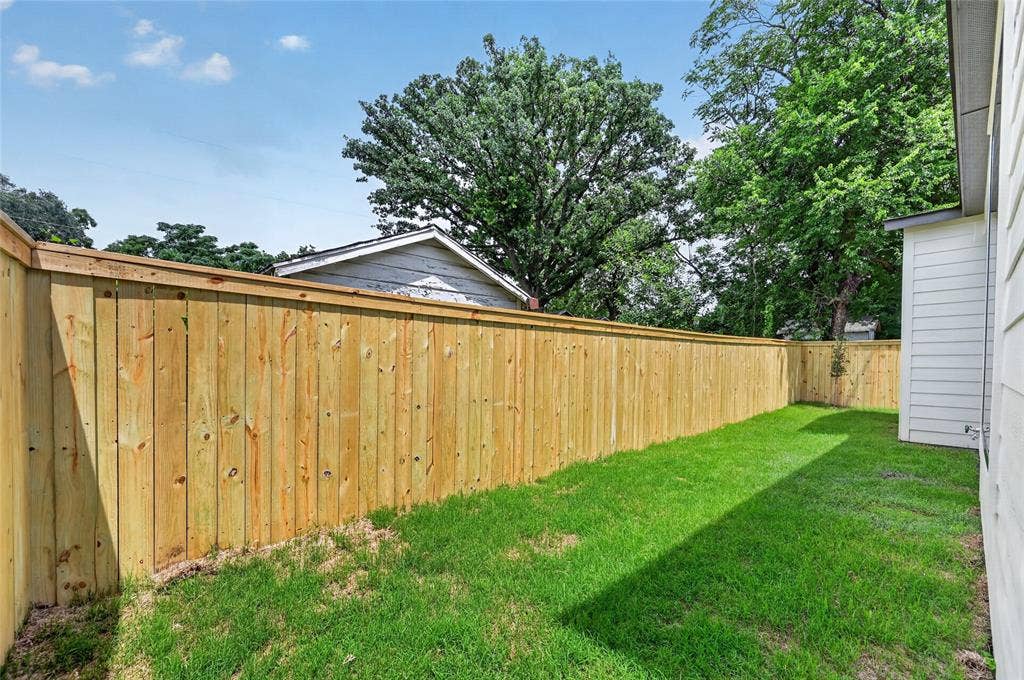 5130 Echo Avenue, Dallas, TX 75215 Private backyard featuring a new wood privacy fence, expansive green lawn, and exterior siding
