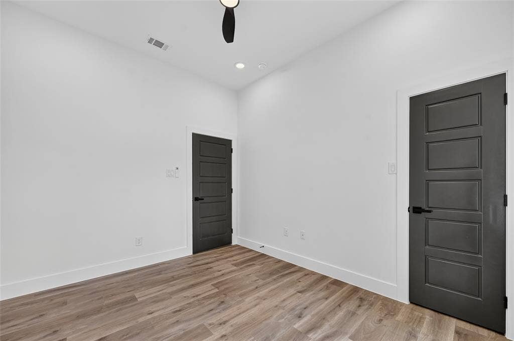 5130 Echo Avenue, Dallas, TX 75215 Room featuring neutral white walls, wood-finish flooring, and two paneled doors with matte black hardware