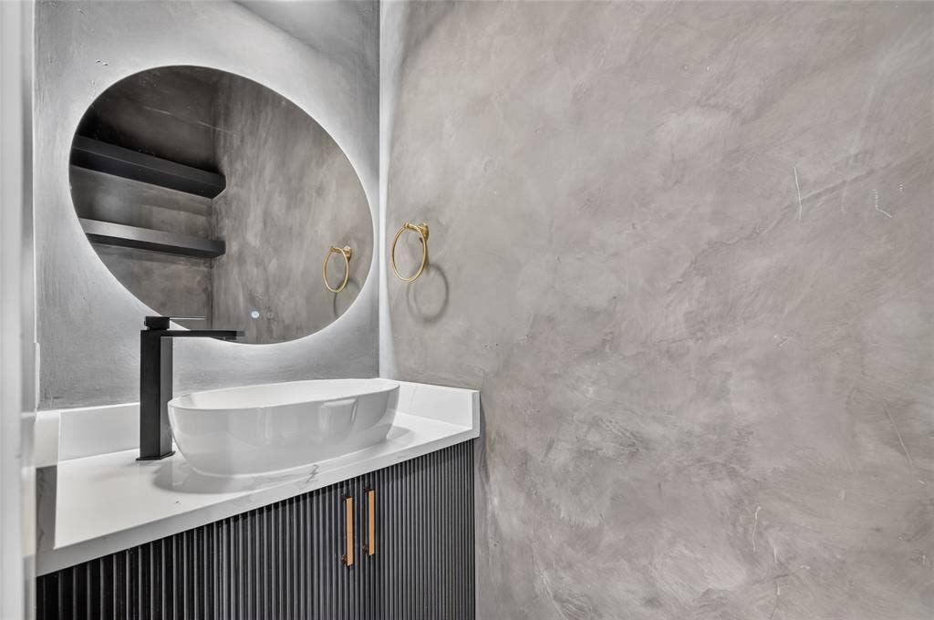 5130 Echo Avenue, Dallas, TX 75215 Modern vanity featuring a white vessel sink, matte black faucet, and a lighted oval mirror