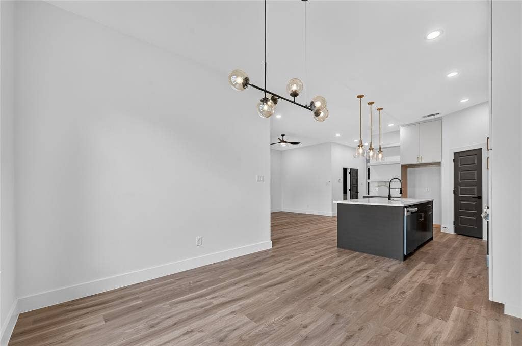 5130 Echo Avenue, Dallas, TX 75215 Open-concept interior featuring wood-finish flooring, a modern chandelier, recessed lighting, a kitchen island with sink and integrated dishwasher, and contrasting dark interior doors