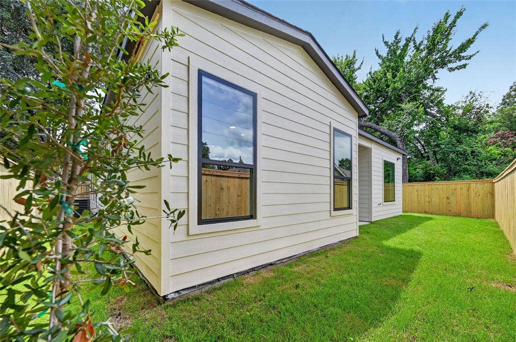 5130 Echo Avenue, Dallas, TX 75215 Expansive side yard featuring a manicured lawn, newly installed wood privacy fencing, and a young tree