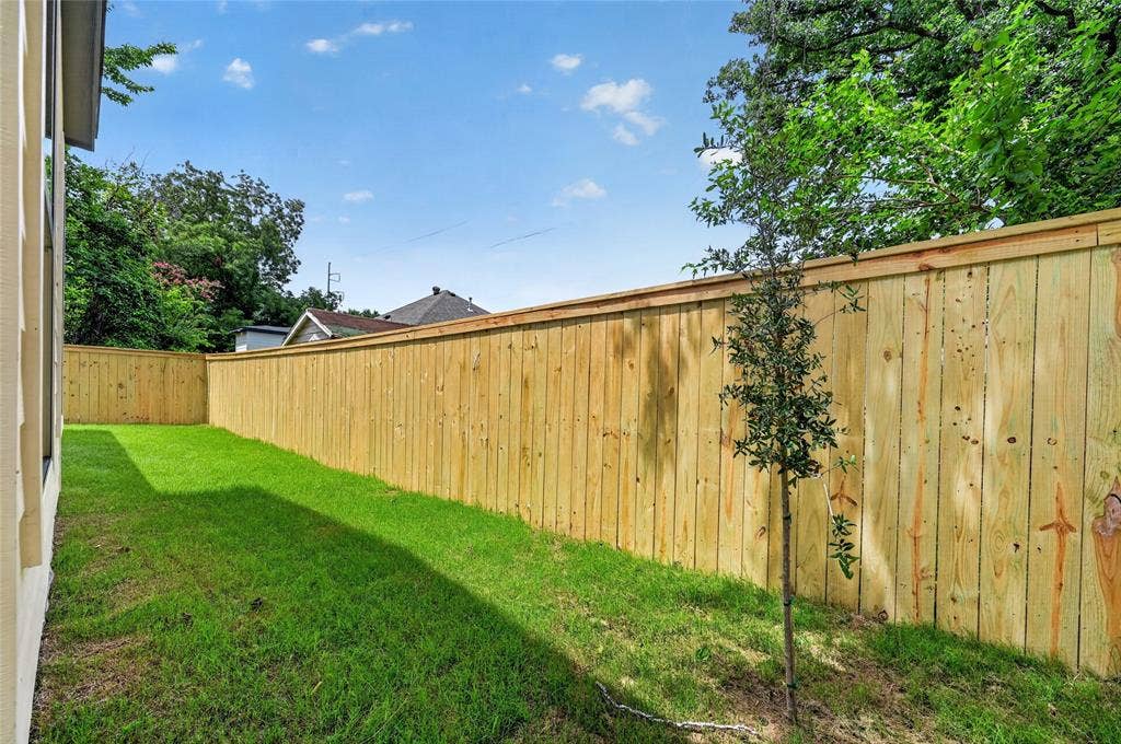 5130 Echo Avenue, Dallas, TX 75215 Expansive green space featuring a newly installed privacy fence, ample room for outdoor activities, and mature trees providing natural shading