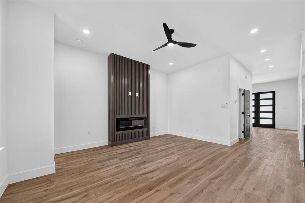 5130 Echo Avenue, Dallas, TX 75215 Spacious room featuring wood-finish flooring, a built-in fireplace with a fluted panel surround, recessed lighting, and a modern ceiling fan