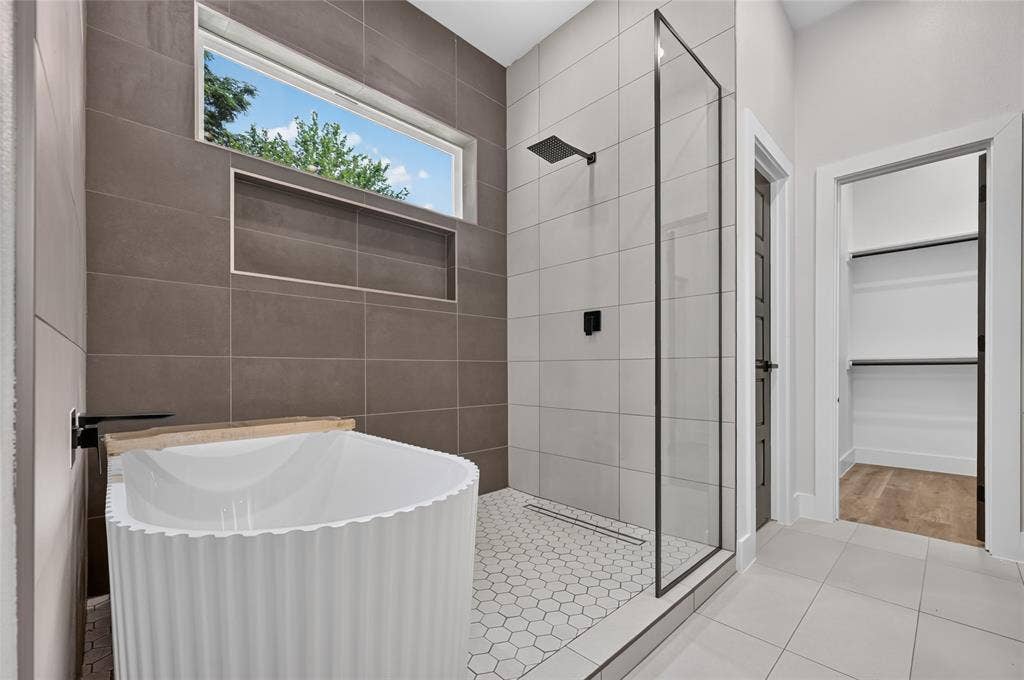 5130 Echo Avenue, Dallas, TX 75215 Contemporary bathroom featuring a freestanding soaking tub with a matte black wall-mounted faucet, a walk-in shower with a frameless glass enclosure and matte black fixtures, a recessed shower niche, and hexagonal tile flooring