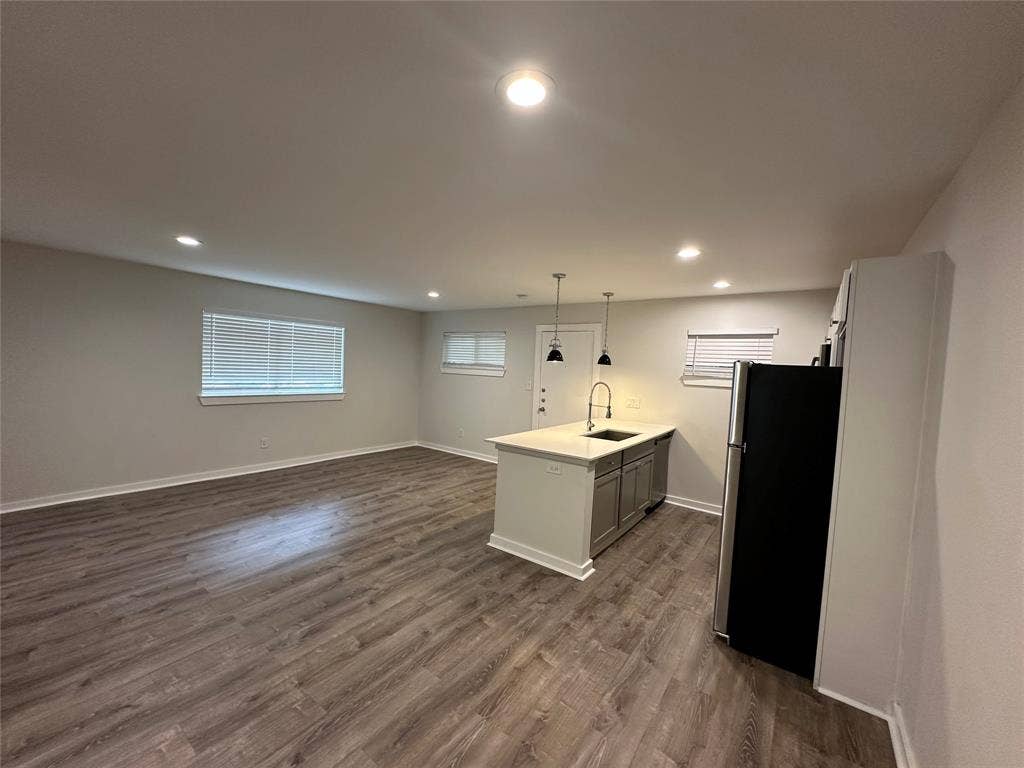 5018 San Jacinto Street, #107, Dallas, TX 75206 Open-concept living space featuring wood-finish flooring, recessed lighting, and a kitchen island with a built-in sink and pendant lighting